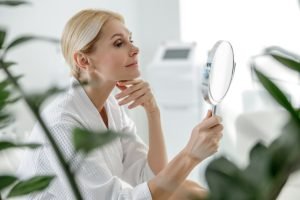 Woman looking at herself in the mirror, slightly smiling.