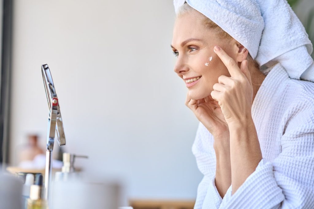 Beautiful woman applying anti aging cream for sensitive skin on her face.