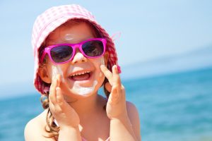 Little girl wearing a hat and sunglasses for sun protection.