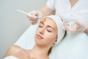 Beautiful woman getting a chemical peel treatment for her uneven skin tone.